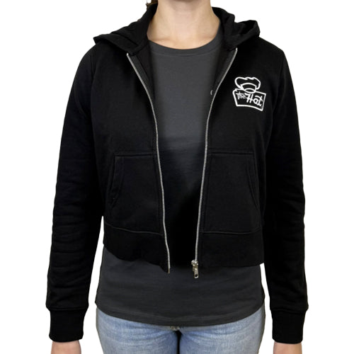 The Hat Exclusive Black hoodie with a logo on the chest worn by a woman on a white background. Adult women's hoodie zipup fleece
